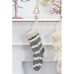 two knit stockings hanging from hooks on a fireplace