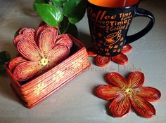 an orange flower sitting on top of a table next to a coffee cup and box