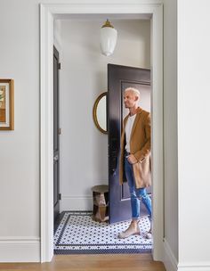 a man standing in front of a door with his hand on his hip and looking into the hallway