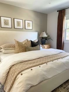 a large bed sitting in a bedroom next to two lamps and pictures on the wall