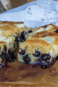 a piece of blueberry cheesecake sitting on top of a wooden cutting board