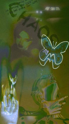 a hand reaching out towards a butterfly on a wall with graffiti in the back ground