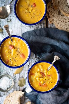 three bowls of soup with bread on the side