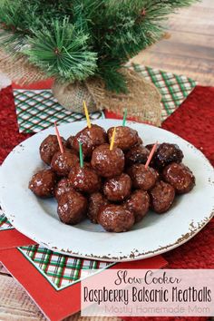 a white plate topped with chocolate covered donuts next to a christmas tree and red napkins