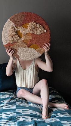 a person sitting on a bed with a rug over their head