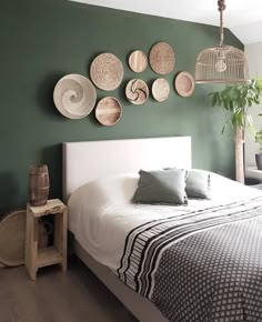 a bedroom with green walls and wicker baskets hanging on the wall above the bed