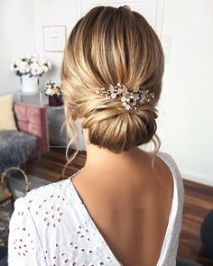 a woman with her hair in a low bun and some flowers on the back of her head