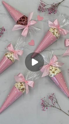 six pink cones with bows and popcorn in them on a marble table next to dried flowers