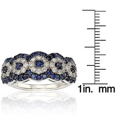 The ring is pave set with 1.03 carats of natural blue sapphires, 1.04 carats of created white sapphires, and a .02 carat fancy brown diamond. This Suzy Levian gallery ring features her unique logo on the inside of the band. Features: Anniversary band Multi-circle design Gold Plated sterling silver High polish Band width is 3-4 mm Ring measures 9 mm long x 23 mm wide x 6 mm high Gemstones: Created white and natural blue sapphires Round-cut Pave setting Total gemstone weight 2.08 carats Diamond: 1 Dazzling Sapphire Ring With Pave Diamond Setting, Sterling Silver Sapphire Ring With Pave Setting, Sapphire Ring With Pave Setting, Sapphire Ring With Pave Setting And Round Cut, Round Sapphire Ring With Pave Setting, Sapphire Cubic Zirconia Ring With Pave Setting, Fine Jewelry Sapphire Ring With Pave Setting, Sapphire Pave Setting Jewelry, Sapphire Jewelry With Pave Setting