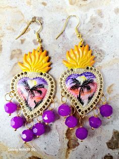 Detailed and beautiful artistically painted earrings, they are painted in detail taking a miniature painting of a beach sunset in purple and pink colors with palm trees in black. Embellished with glass beads, the hooks are hypoallergenic, the earrings are protected with several layers of high-quality jewelry varnish, improving the quality and durability of the earrings' paint. These earrings are inspired by our Mexican culture and hand painted; They are the ideal gift because they combine with any outfit both day and night, enhancing the beauty of the person who receives them and attracting attention for being unique hand-painted pieces, the Ideal gift for Mother's Day and holidays. Features/ Product info Note: Each earring is hand painted, there are small differences between each pair, so Artistic Hand-painted Purple Earrings, Bohemian Heart-shaped Beaded Earrings For Gifts, Bohemian Heart-shaped Beaded Earrings As Gift, Bohemian Hand Painted Purple Earrings, Purple Hand Painted Bohemian Earrings, Handmade Bohemian Dangle Heart Earrings, Handmade Artisan Heart Earrings, Handmade Purple Earrings For Valentine's Day, Artisan Hand Painted Earrings For Festival