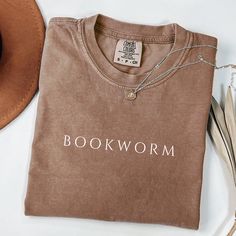 This cozy and stylish tee is perfect for any book lover who wants to wear their passion proudly. Whether you're a librarian, teacher, or just love to get lost in a good story, this shirt is for you. The Comfort Colors fabric ensures a soft, comfortable fit, making it the ideal choice for long reading sessions. It's also a thoughtful gift for the bookworm in your life or a fellow reader who enjoys expressing their love for literature. Embrace your inner book lover with this classic, bookish shirt Book Club Shirt Ideas, Bookish Tees, Bookish Tshirt, Club Tshirt, The Bookworm, Bookworm Shirt, Book Shirt, Librarian Shirt, Reading Shirts