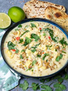 a bowl filled with soup next to bread and lime