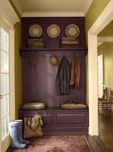 an entryway with coat racks, baskets and coats hanging on the wall next to it