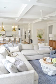 a living room filled with white furniture and lots of pillows on top of it's couches