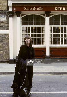 a woman is standing on the street with her dog