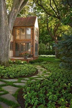 a small house surrounded by lush green trees and shrubbery in front of a tree