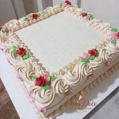 a large white cake with pink and red flowers on it's edges is sitting on a table