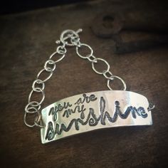 "\"You Are My Sunshine\". Are you singing already? This bracelet is a little piece of happy. This bracelet is lovingly made from recycled fine silver, and 2 sets of sterling silver chain. It is finished with a toggle clasp. The silver artwork charm is approximately 1 3/4 inches across and 1/2 inch wide. If you require a bracelet size other than a standard 7 inches, simply leave me a note during checkout with your desired size. Not familiar with fine silver? Here are the facts: Fine silver has a Inspirational Handmade Name Bracelet For Everyday, Adjustable Bohemian Sterling Silver Chain Bracelet, Everyday Inspirational Handmade Name Bracelet, Inspirational Handmade Name Bracelet, Adjustable Bohemian Sterling Silver Bracelet Gift, Adjustable Bohemian Sterling Silver Bracelet For Gifts, Handmade Inspirational Friendship Bracelet, Handmade Inspirational Friendship Name Bracelet, Inspirational Handmade Friendship Name Bracelet