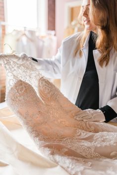 a woman in a white jacket is looking at a wedding dress