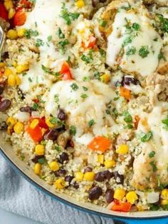 a skillet filled with chicken, rice and veggies on top of a blue towel