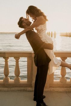 a man and woman are dancing by the water