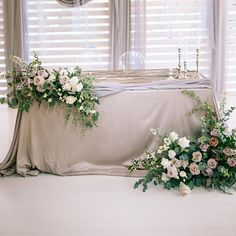 flowers and greenery are arranged on the table for an elegant wedding ceremony in front of large windows