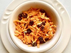 a white bowl filled with raisins on top of a table next to a fork