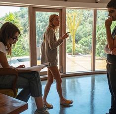 a group of young people standing around each other in a room with glass doors and windows