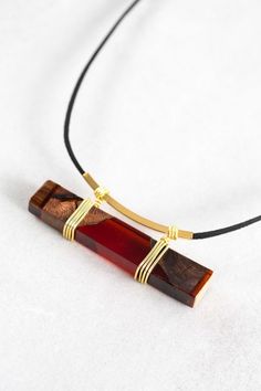 a necklace with a wooden pendant on a black cord and gold plated clasps