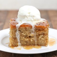 a piece of cake with ice cream on top is sitting on a white plate and sits on a wooden table