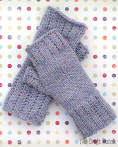 two gray knitted mittens sitting on top of a polka dot covered tablecloth