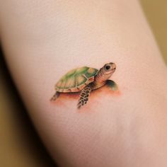 a small turtle tattoo on the back of a woman's leg