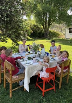 a group of people sitting around a table with plates and cups in front of them