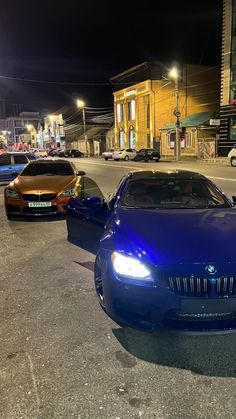 two cars parked on the side of the road in front of some buildings at night