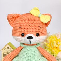 a crocheted teddy bear with a green dress and yellow bow on its head