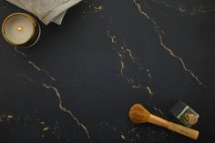 a black counter top with a brush and candle next to some towels on it's side