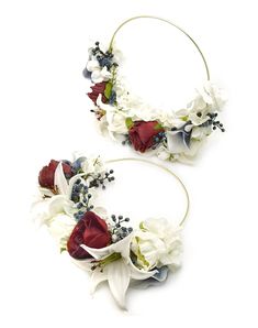 two white and red flowers are attached to hoops on the headband, both with blue accents