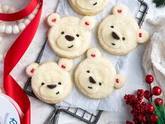 cookies decorated like teddy bears are on a tray next to red ribbon and christmas decorations