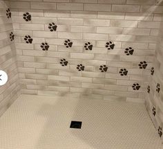 a tiled shower with paw prints on the wall and in the floor, it is white