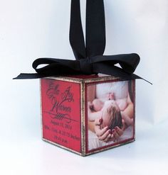 a red box with a black ribbon tied around it that has an image of a baby on it