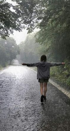 a person walking in the rain with their arms outstretched