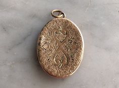 "This beautiful antique pendant is a gold filled locket in the shape of an oval. Small designs are etched on both sides of the pendant, complimenting the main double heart engraved on the front. The inside of the locket is double sided and can hold two photos. This is a Victorian era piece of mourning jewelry, used to remember loved ones who had passed on. Inside the locket, the roman numerals VIII have been carved in two places. There are also very light etchings of a name. Measurements: Locket Victorian Oval Locket Necklace With Vintage Charm, Oval Victorian Locket Necklace With Vintage Charm, Antique Etched Oval Locket Necklace, Antique Oval Pendant Locket Necklace For Memorials, Ornate Oval Locket Necklace From Vintage Collection, Antique Gold Oval Locket Necklace, Antique Gold Oval Locket Necklace For Anniversary, Antique Gold Oval Locket Necklace For Keepsake, Victorian Oval Locket Necklace Keepsake