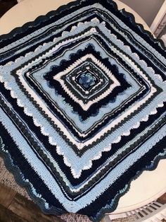 a crocheted blanket sitting on top of a table next to a white chair