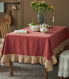 a dining room table with flowers and teapots on it, next to two chairs