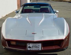 the back end of a white corvette car parked in a parking lot next to a building