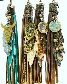 three different types of tassels hanging from hooks on a white wall, one with an animal's head and the other with feathers attached to chains