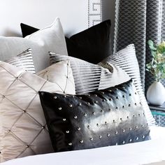 a bed topped with lots of black and white pillows