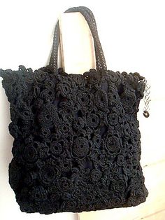 a black crocheted bag hanging on a wall