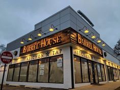 the exterior of a bar called barrel house with lights on and windows lit up at night