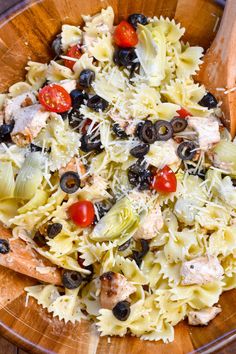 a wooden bowl filled with pasta and olives